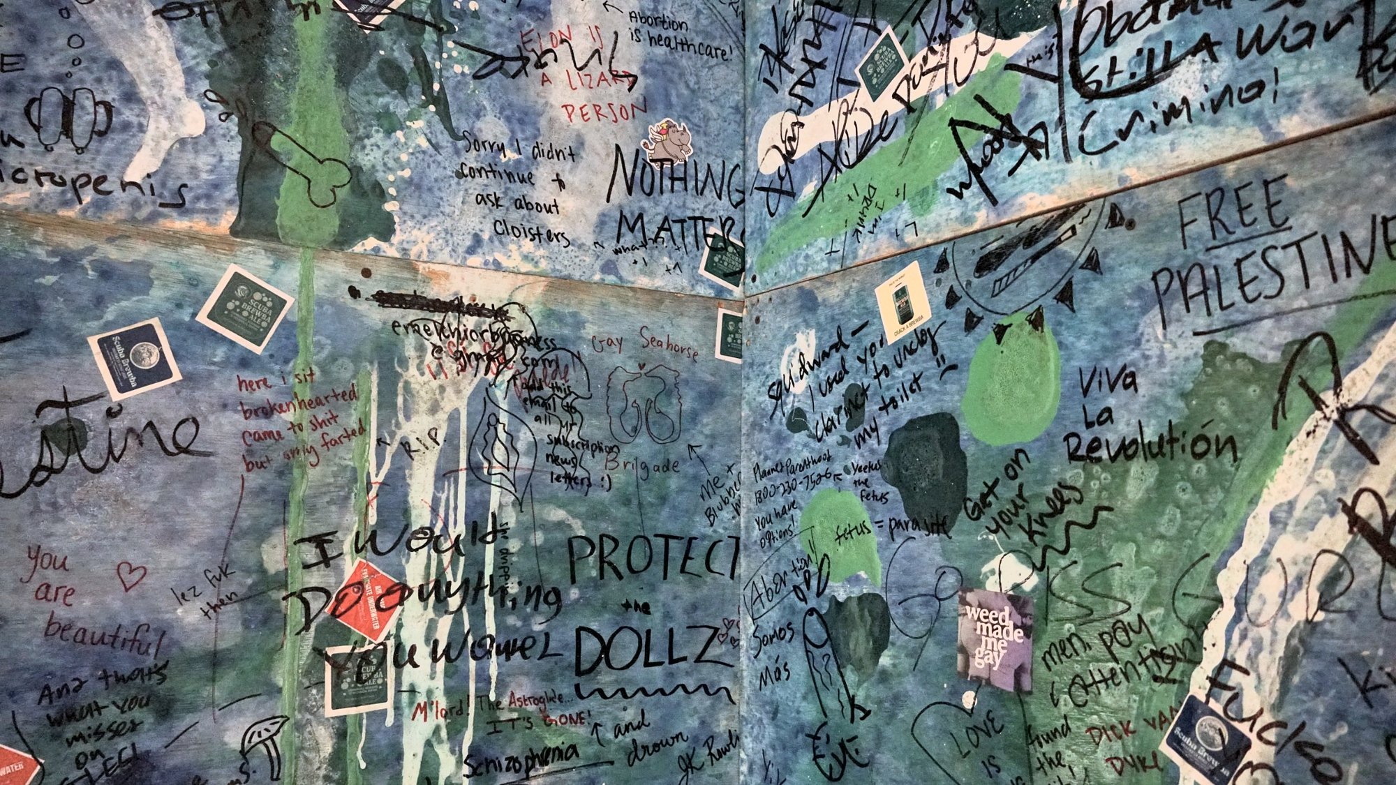 Club bathroom walls covered in visitor graffiti and Scuba Brewba stickers